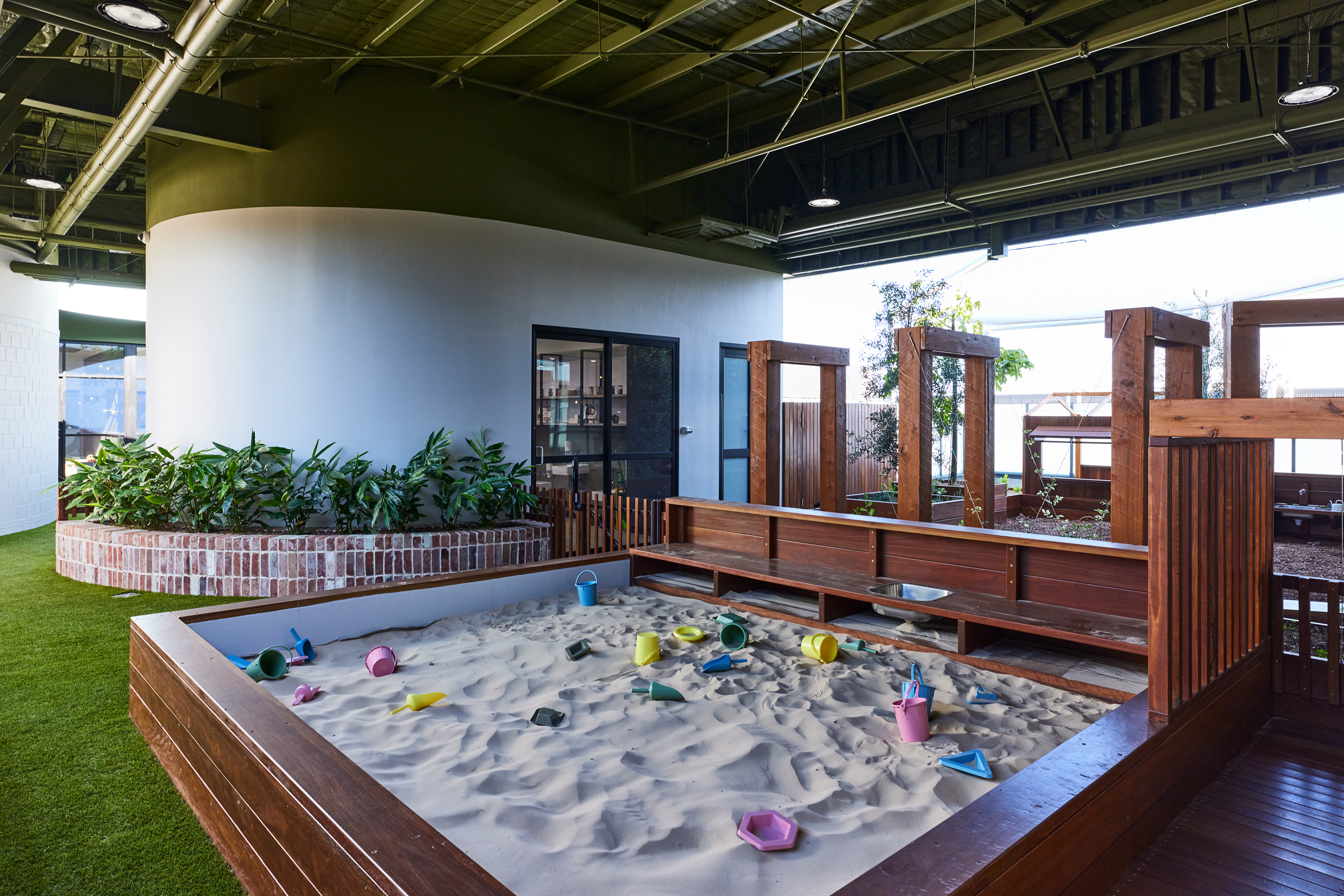 Sand play area with timber cubby structure and sensory play equipment