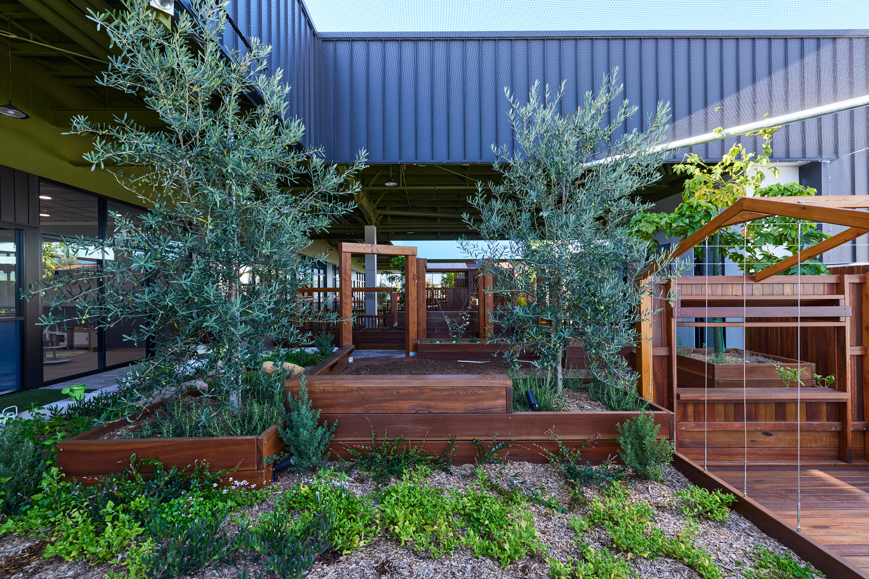 Indoor-outdoor transition zone with glass walls and natural play elements