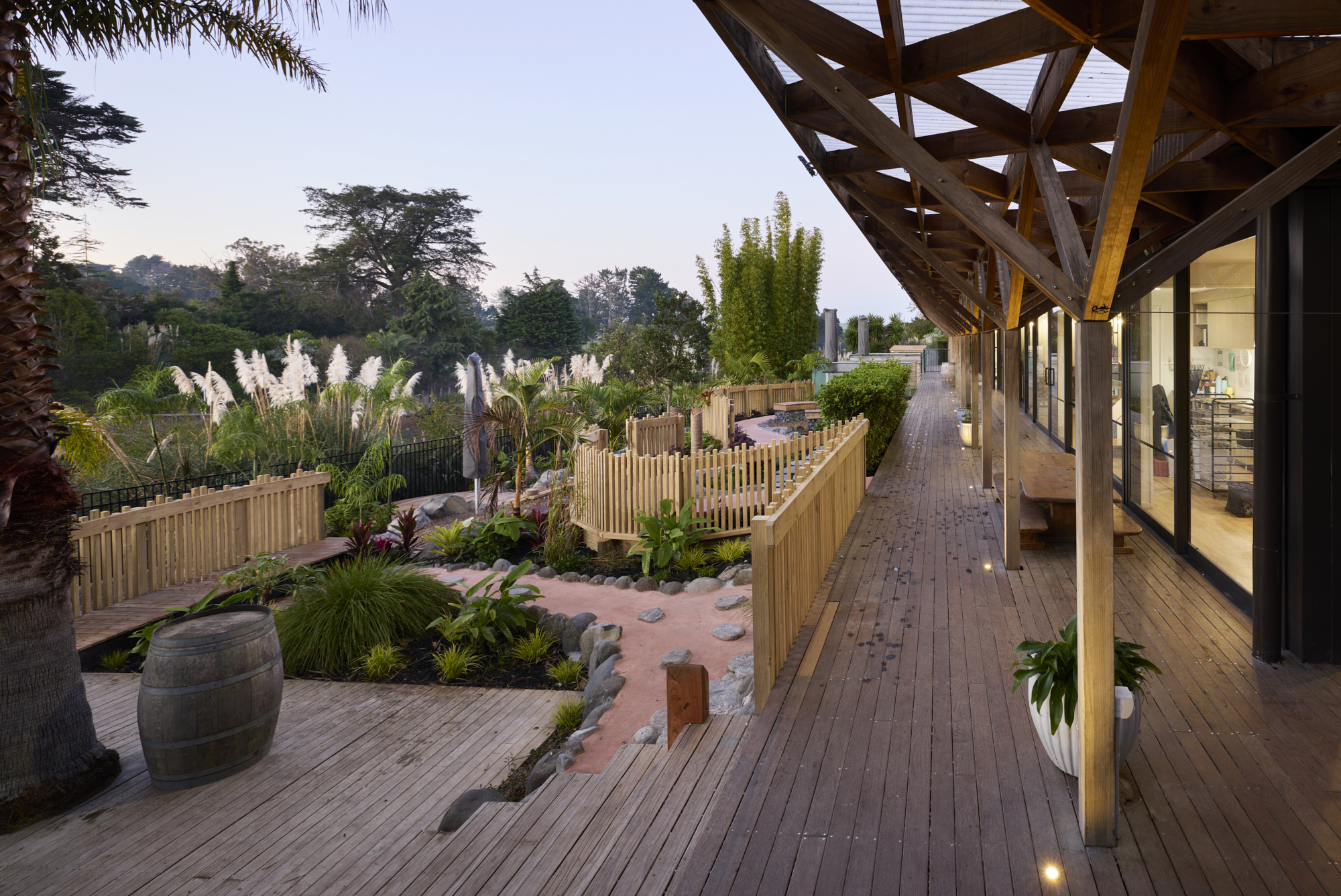 Timber boardwalk alongside building with stone stepping pads, tropical plantings and timber pergola overhead