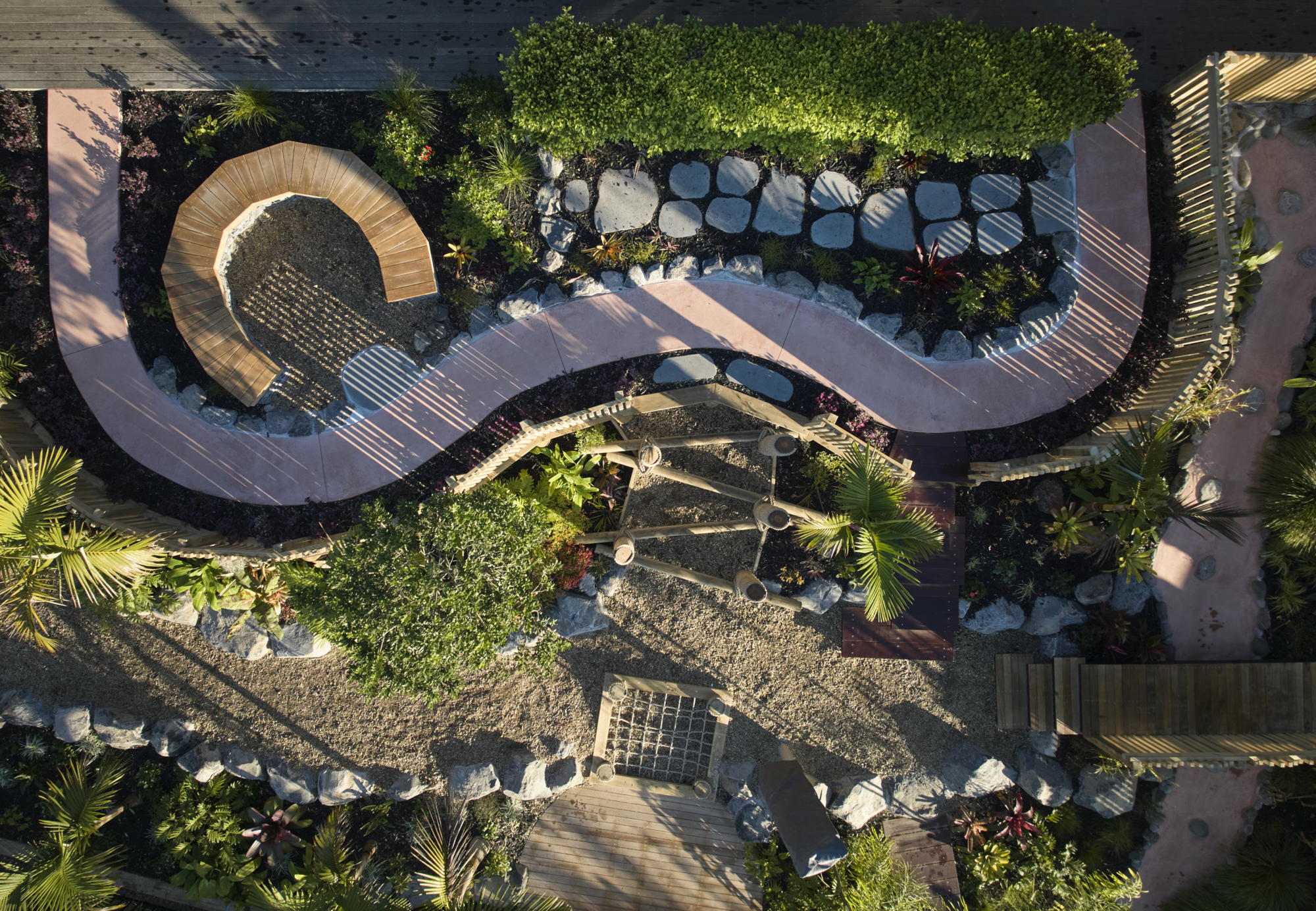 Overhead view of curved pathway with circular timber seating bench, stone stepping pads and planted garden beds