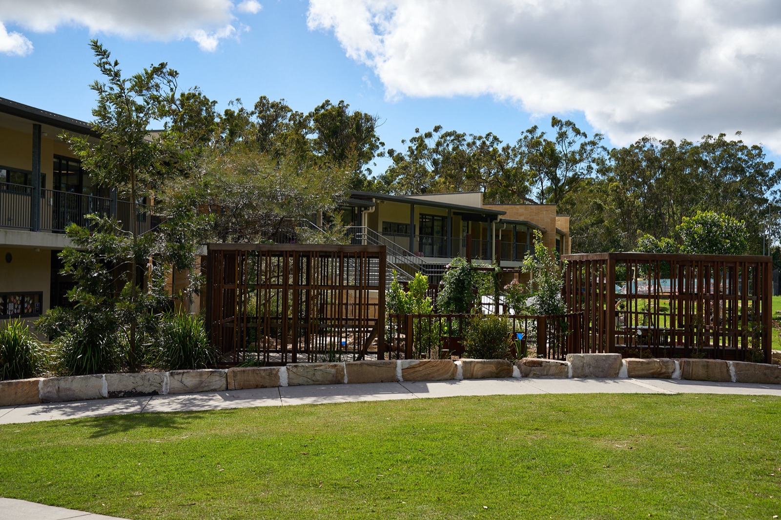 Timber screen structures framing the lawn and campus buildings
