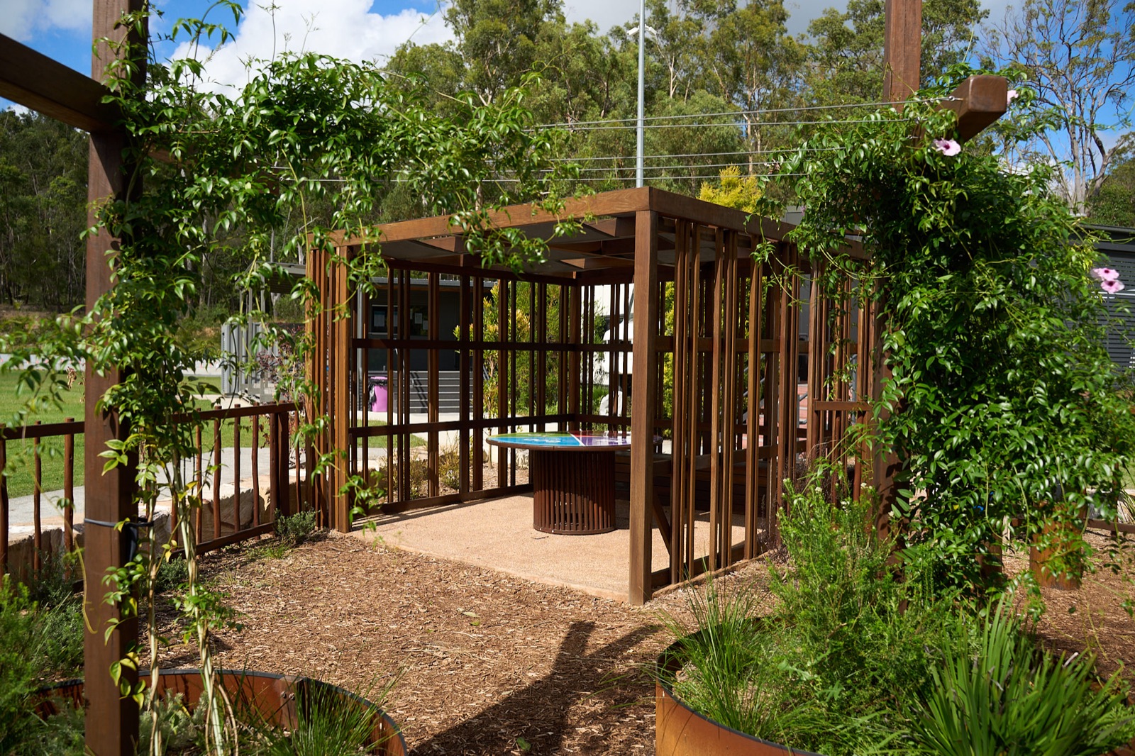 Vine-covered timber pavilion with gathering space