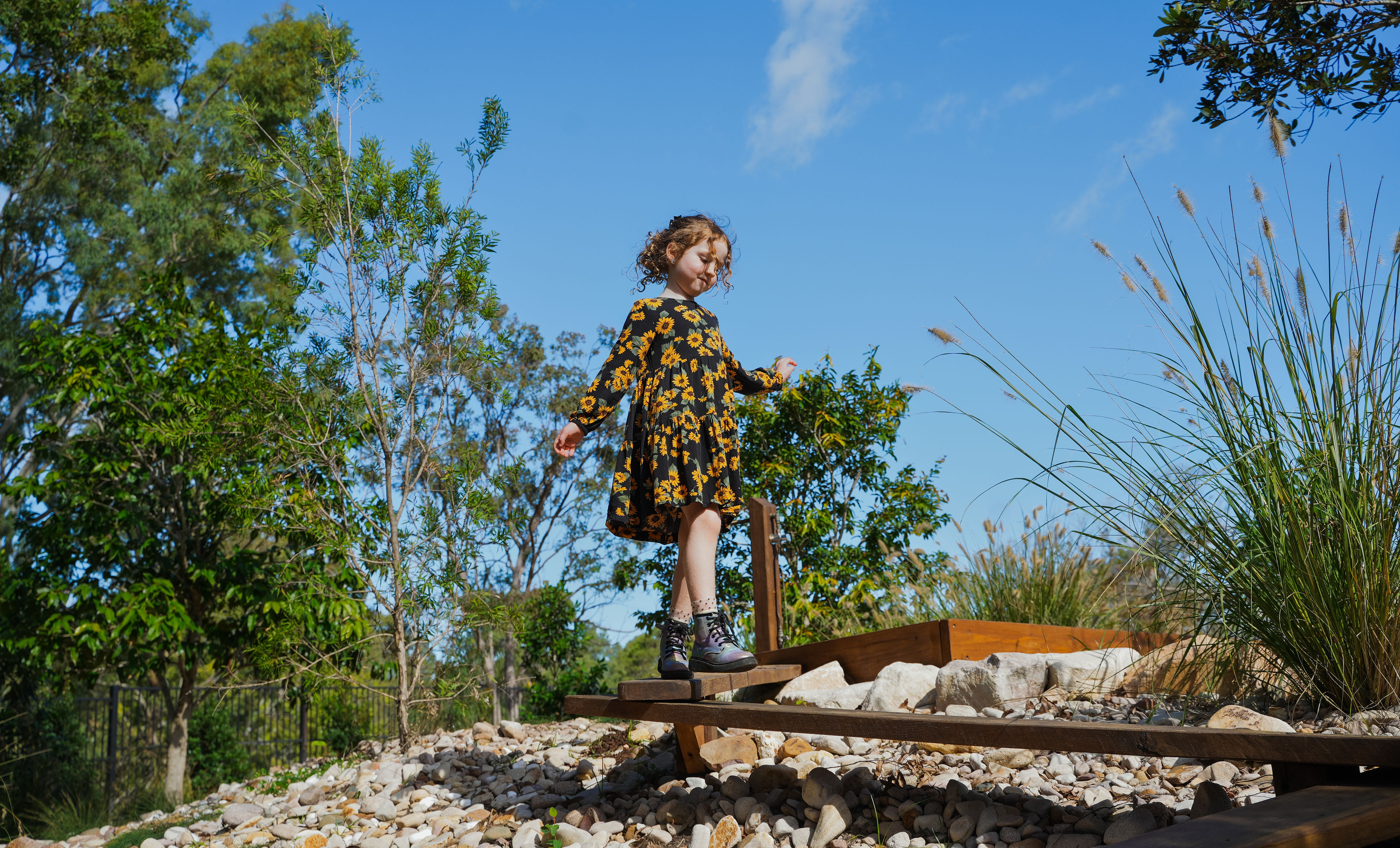 A child balancing along a timber beam over the rock creek bed