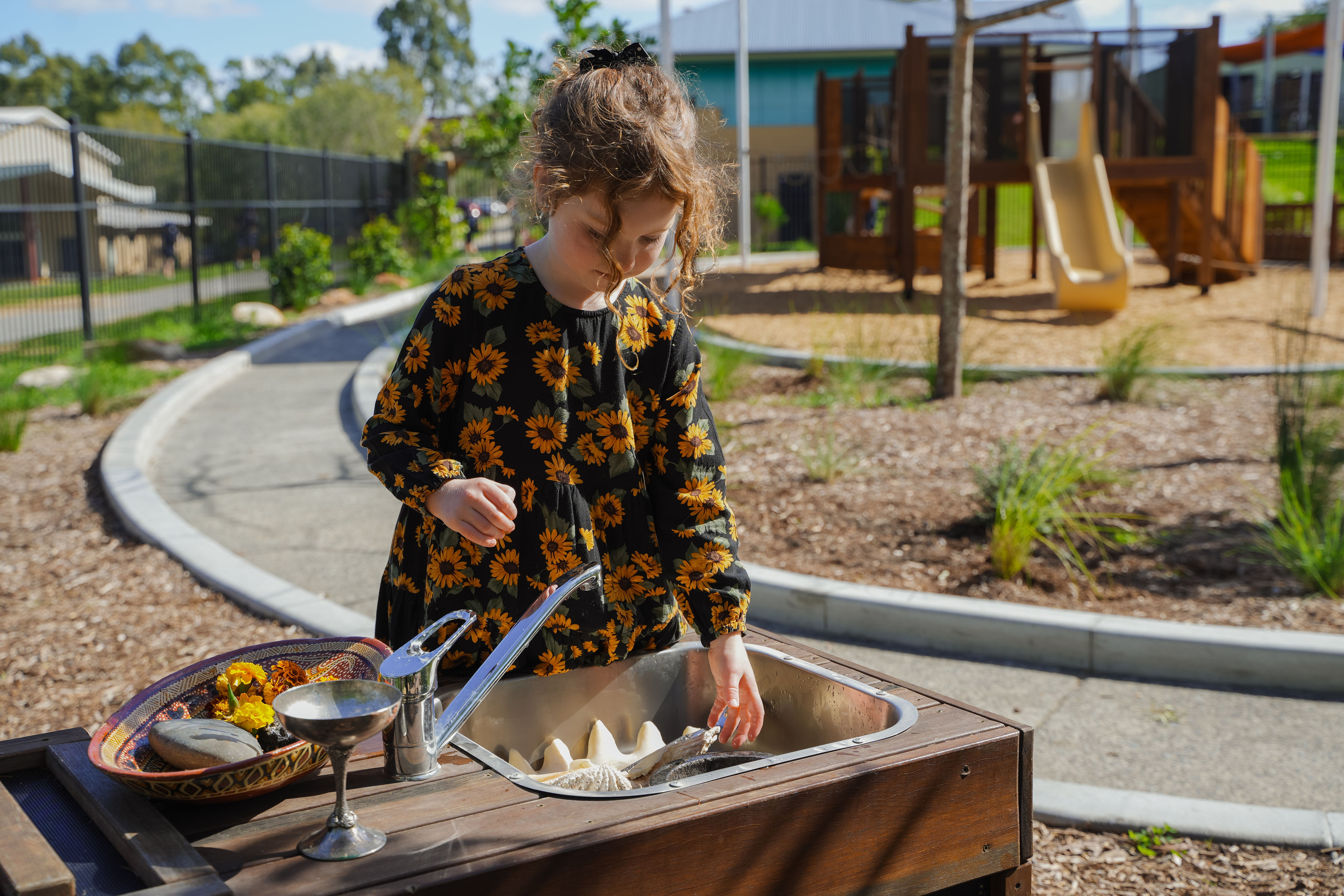 A child at the mud kitchen with shells and stones