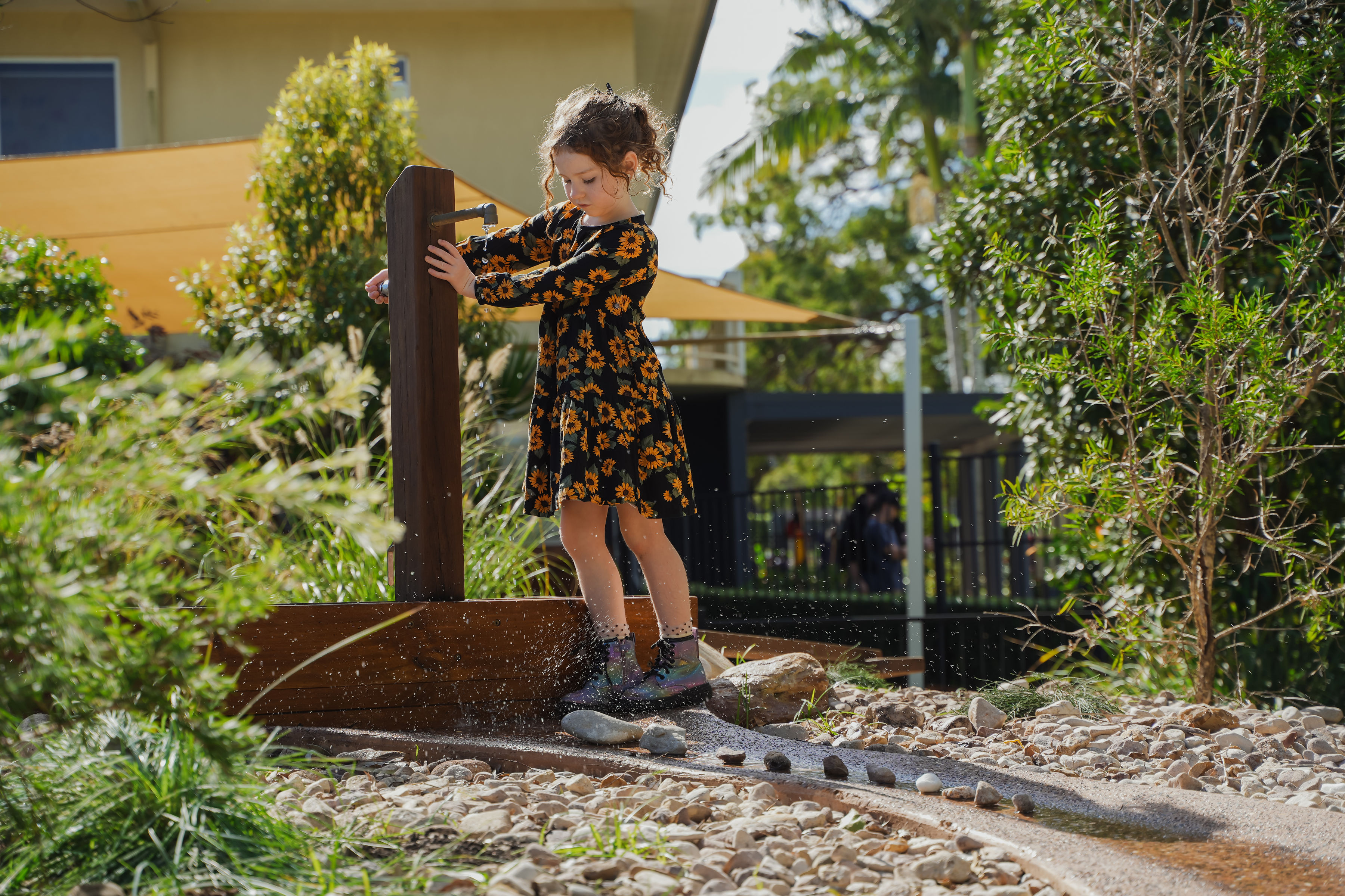 A child playing at the water tap feature that feeds the rock creek bed
