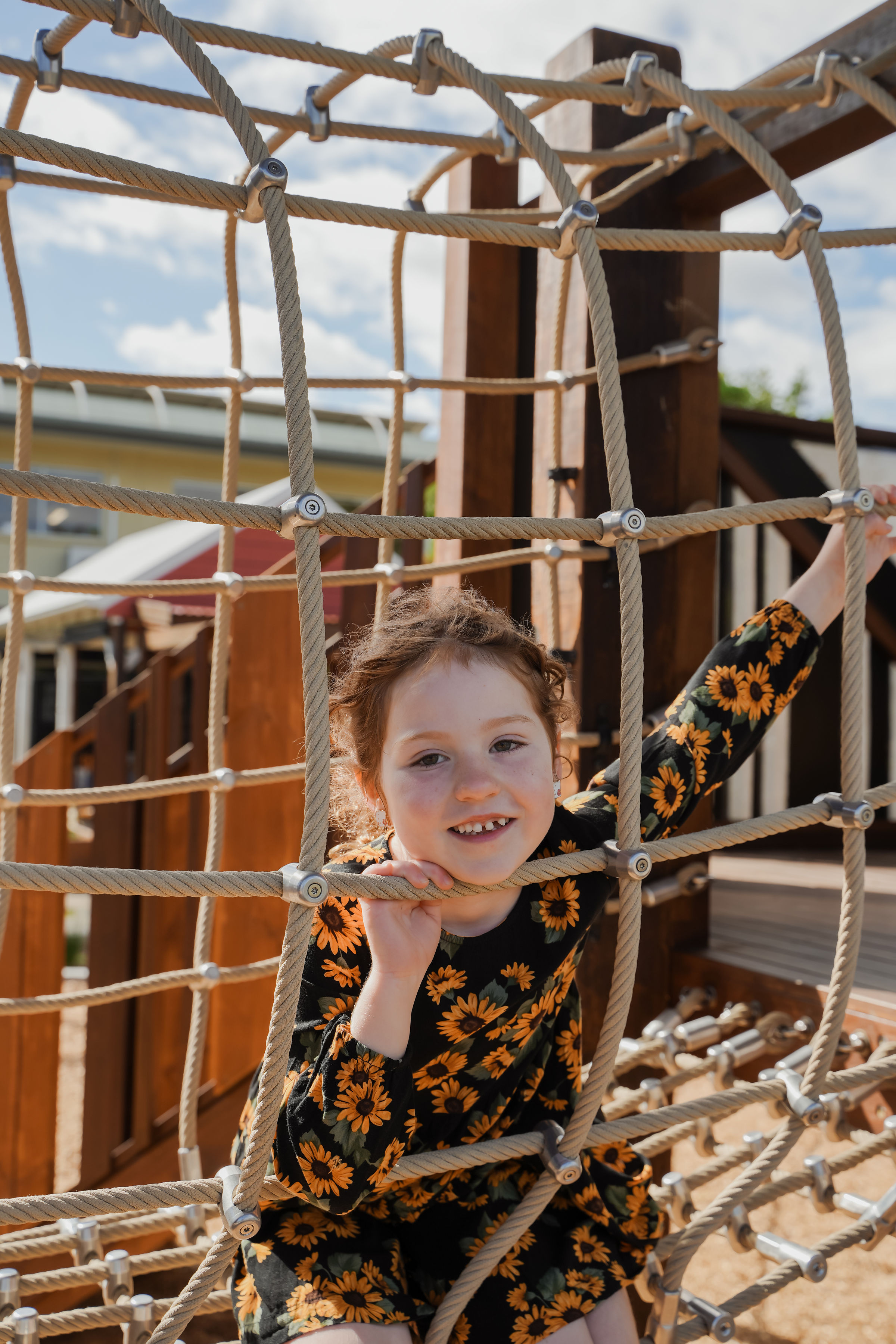 A child peeking through the rope climbing net