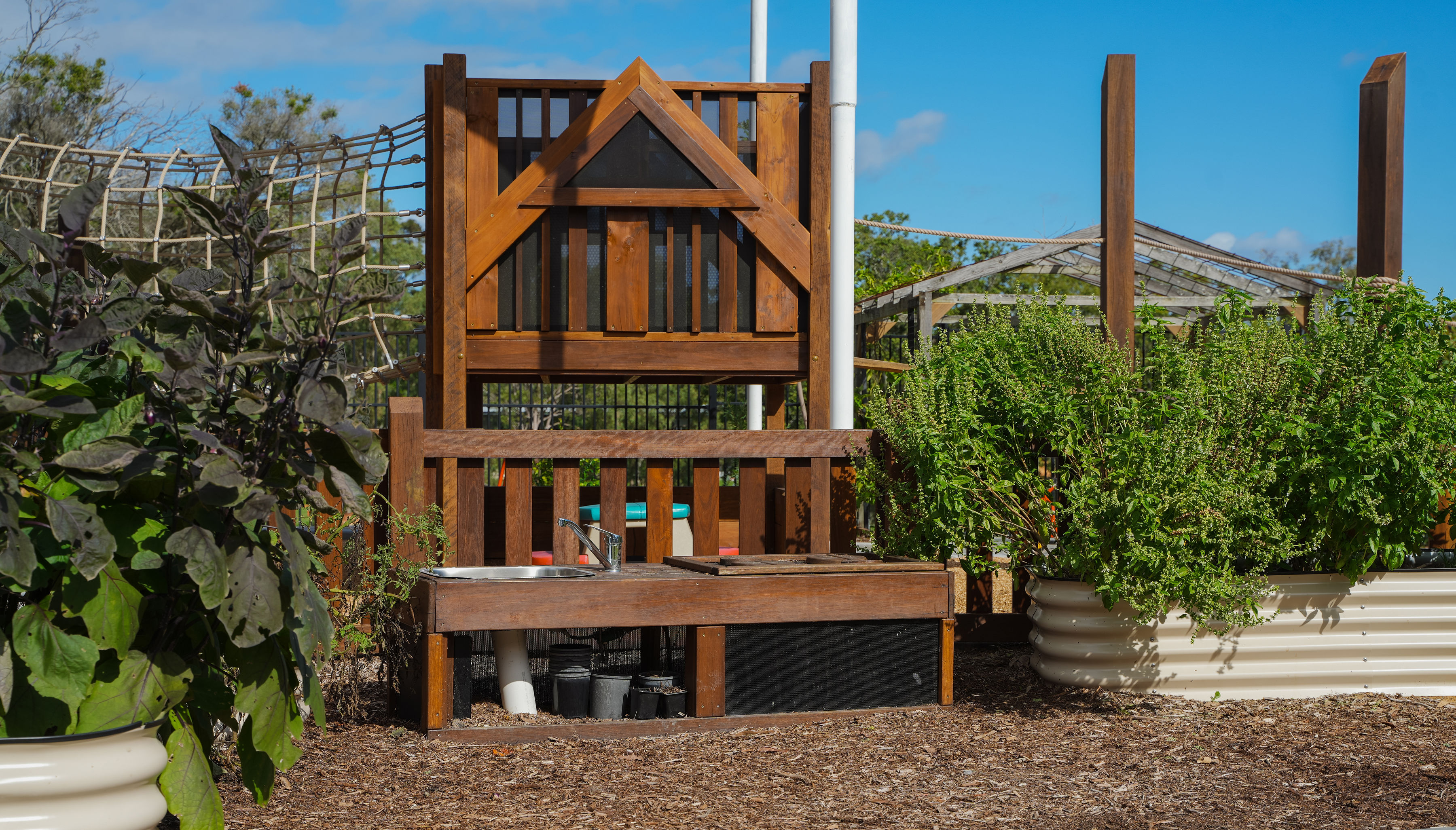 The mud kitchen with the rope bridge in the background