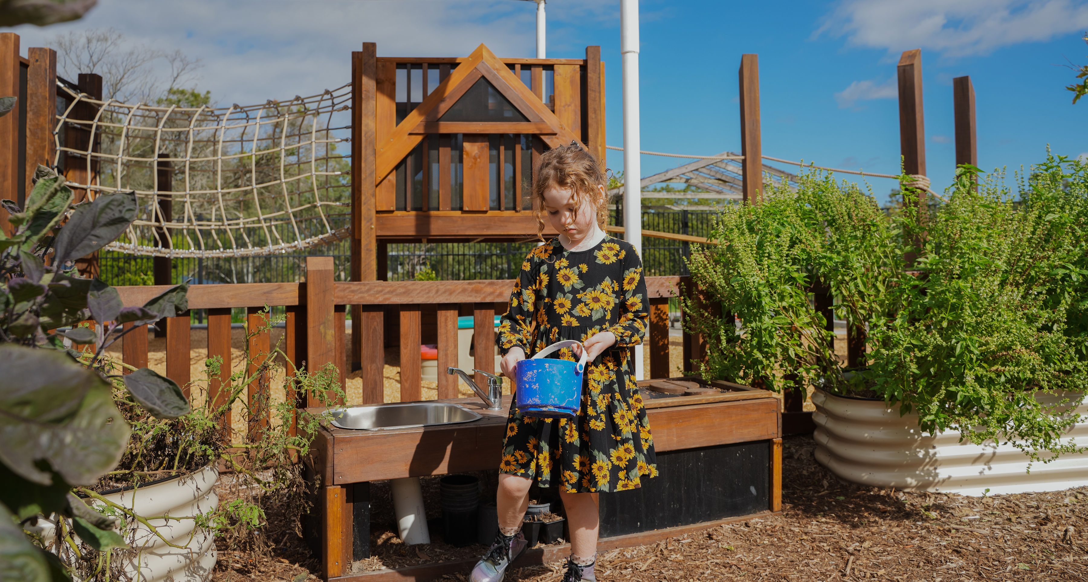 A child watering the vegetable garden beds
