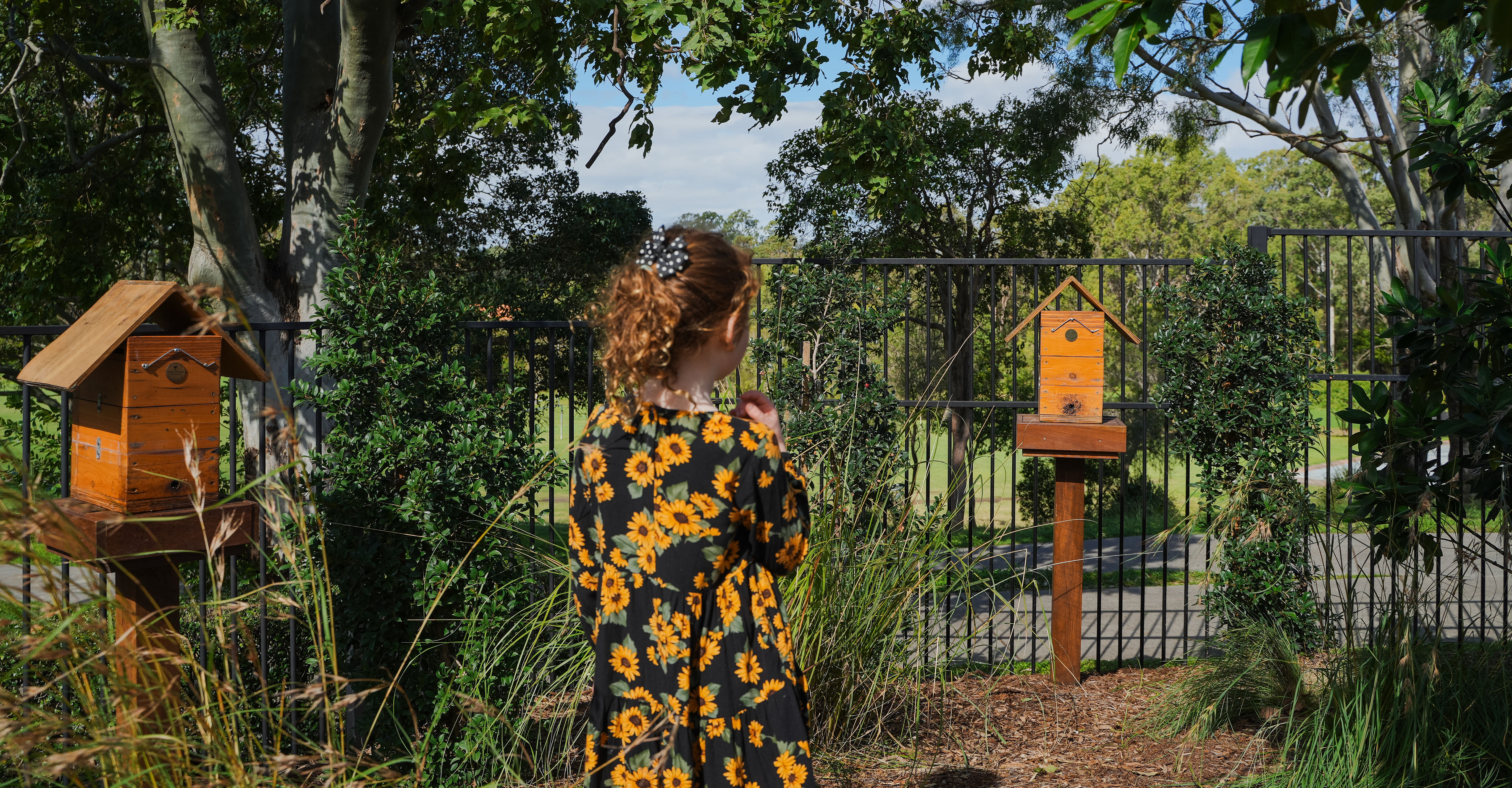 A child inspecting the insect hotel along the fence line