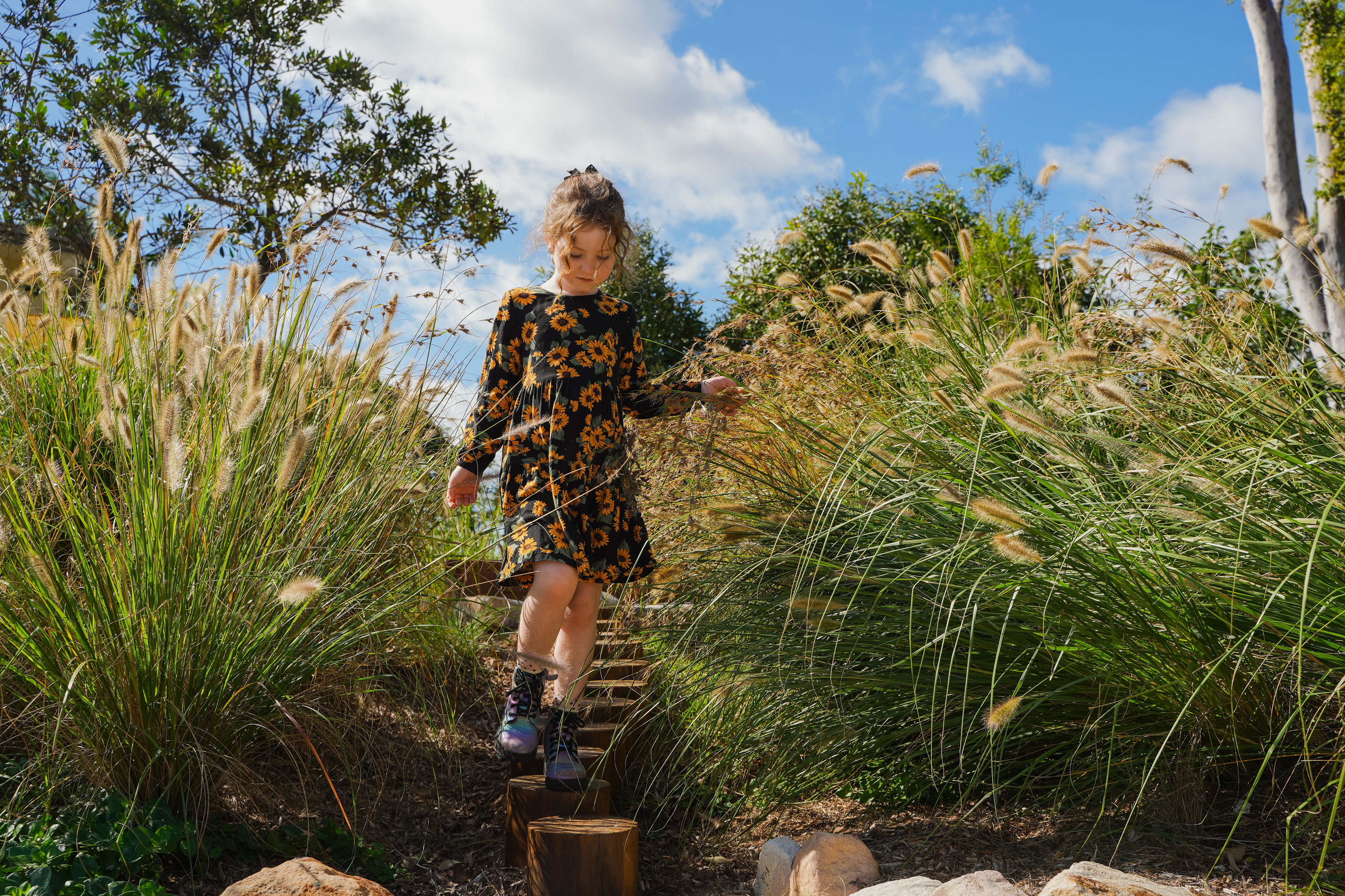 A child walking across the timber log-round stepping trail