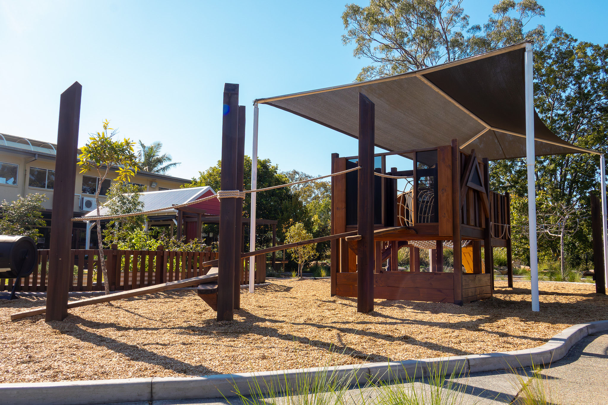 The multi-level play tower with rope bridge and shade sails