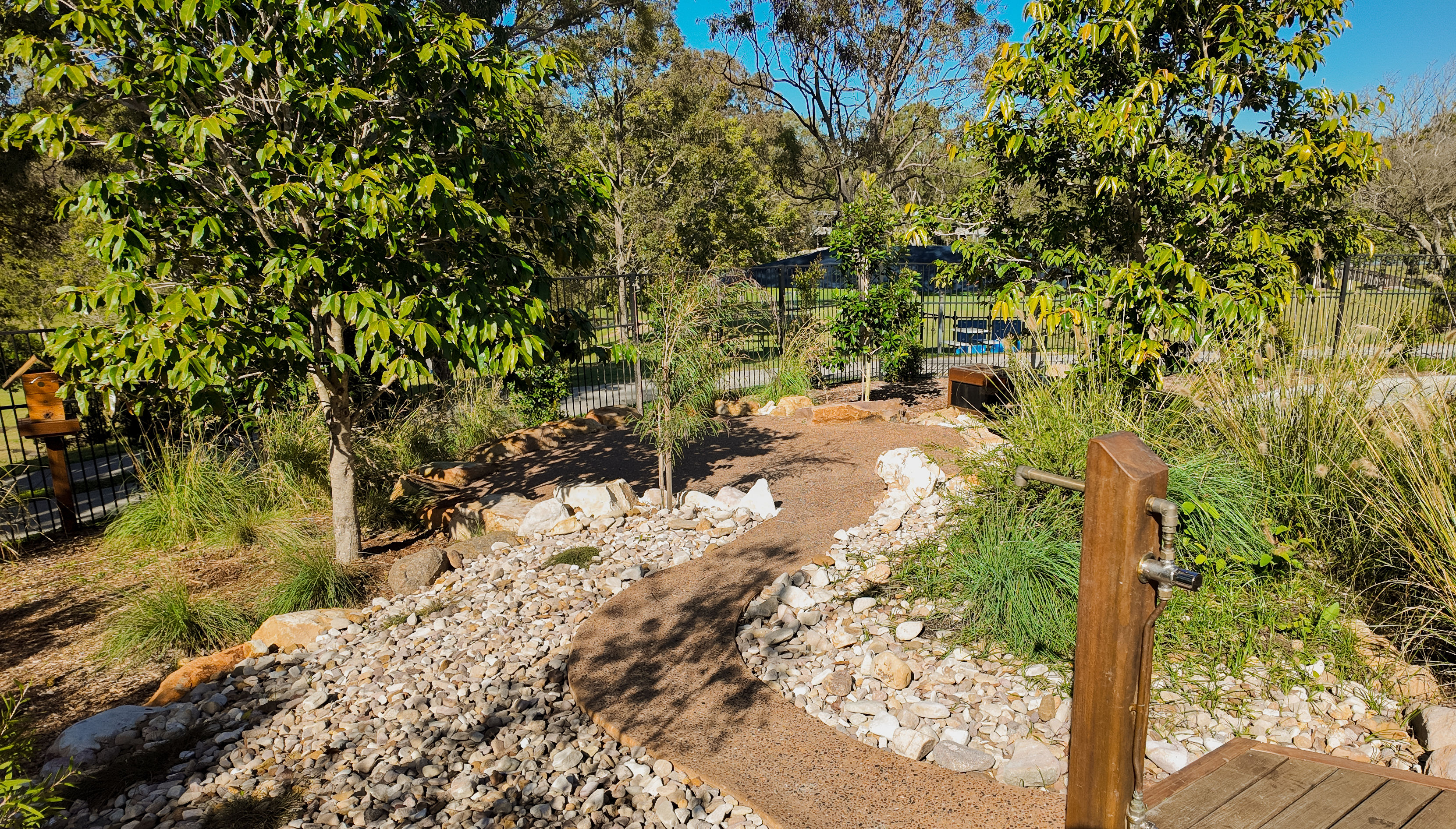 Wide view of the nature play zone, rock creek bed, and water tap