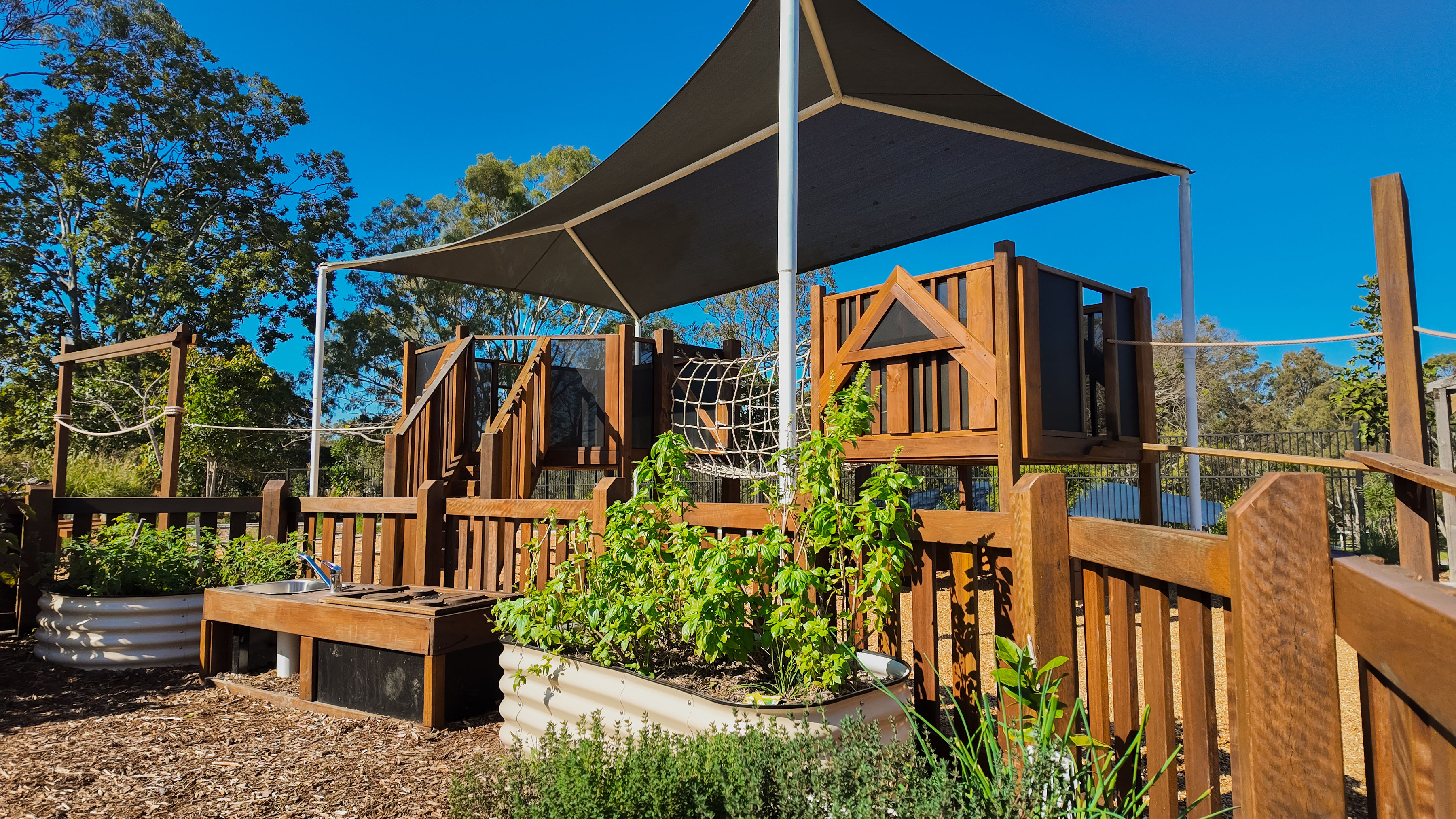The sustainability zone with vegetable planters and mud kitchen beneath the play tower
