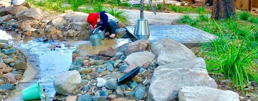 Child playing with water among rocks in a natural creek bed